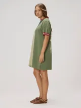 Vestido corto de punto tricolor, con diseño de bloques en tonos turquesa, celeste y azul marino. Presenta cuello redondo y puños con líneas en tonos tostado y blanco, además de un sutil bordado en el pecho.