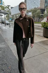 Chaqueta corta de paño en color beige, con cuello subido, manga larga y cierre frontal cruzado con botones oscuros. Presenta bolsillos delanteros de vivo.