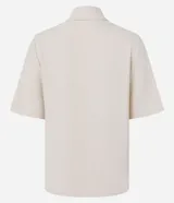 Camisa color fucsia de tejido airflow, con cuello camisero, mangas cortas con pliegues, cierre frontal con botones metalizados y bolsillos con solapa en el pecho.