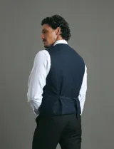 Chaleco de vestir color azul oscuro con textura sutil, corte clásico, cierre frontal con botones y bolsillos laterales simulados.