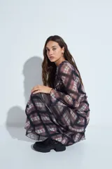 Falda larga de corte fluido con estampado de cuadros en tonos oscuros, rojizos y blancos. Presenta un diseño ligero con terminaciones onduladas en el ruedo.