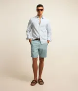 Bermuda celeste confeccionada en sarga de algodón, con trabillas en la cintura, cierre de botón y cremallera, y bolsillos laterales y traseros.