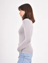 Polera de punto color gris claro, de corte al cuerpo y manga larga, con cuello alto vuelto.