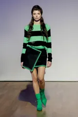 Minifalda de corte cruzado con diseño asimétrico, confeccionada en material tipo gamuza color negro, con bordes en textura de sherpa en color verde lima.