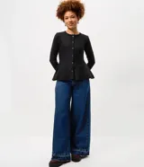 Saco de tricot negro con diseño peplum, cuello redondo, mangas largas y cierre frontal con botones. Presenta un corte ajustado en el torso que se ensancha en la cintura.