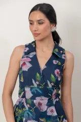 Vestido midi de organza azul marino con estampa floral en tonos rosados y verdes. Presenta escote en V cruzado con solapas, sin mangas, falda evasé de capas asimétricas y estructuradas.