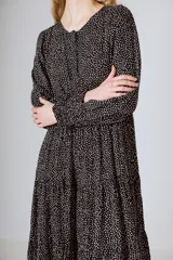 Vestido midi negro con corte en la cintura y falda amplia con volados.