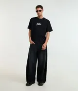 Remera de algodón negra, corte boxy (holgado), con estampado grande en la espalda de alas grises y el texto "Fallen The Chains east. 1998".