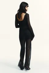 Pantalón negro de tiro alto con cintura elástica y pierna recta. Confeccionado en tela semitransparente, con forro corto interior a tono.