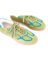 Championes de estilo deportivo retro, confeccionados en una combinación de cuero y gamuza en tonos verde palta y detalles en azul vibrante. Presentan suela de goma color caramelo con textura estriada y cordones al tono.