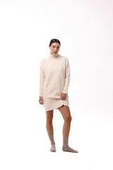 Vestido tejido de punto color beige, con cuello alto y silueta relajada, de manga larga y diseño minimalista.