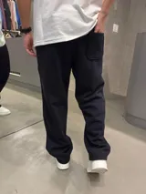 Pantalón deportivo negro de algodón con corte oversize, cintura elástica, bolsillos laterales, costuras frontales en relieve y pequeño estampado en la pierna izquierda.