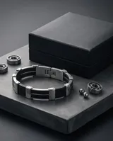 Pulsera de diseño moderno compuesta por una banda central de goma negra flanqueada por piezas de acero inoxidable con grabado de guarda griega.
