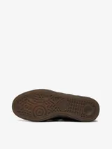Mocasín Adidas Handball Spezial confeccionado en ante negro, con diseño inspirado en el modelo icónico de la marca. Presenta las tres bandas laterales dentadas, detalle de logo del trébol en dorado y suela de goma color caramelo.
