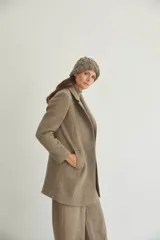 Saco corto entallado de lana fina, con cuello solapa, manga larga y cierre frontal con botones. Presenta un diseño clásico con textura de espiga en tonos tierra.