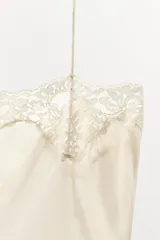 Vestido midi tipo lencero de viscosa, color beige, con escote recto, tirantes finos y detalles de encaje a tono en el escote y el ruedo.