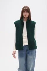 Chaleco sin mangas de textura peluche (teddy) color crema, con cuello alto y cierre frontal de cremallera.