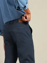 Pantalón de vestir color beige, de corte recto, con bolsillos laterales y traseros. Se ajusta a la cintura con cinturón de cuero marrón.