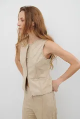 Chaleco de gamuza color caramelo, con cierre frontal de botones y bolsillos laterales simulados.