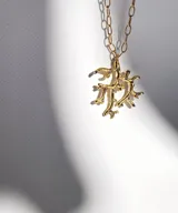 Collar con cordón de cuero negro y dije plateado con forma de coral con incrustaciones de piedras celestes.