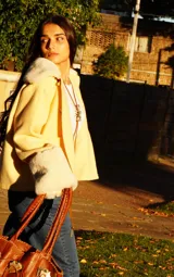 Campera amarilla con cuello y puños de piel sintética color crema, corte recto y bolsillos laterales.