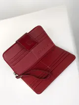 Billetera grande de cuero vacuno con textura granulada y detalles en charol. Cuenta con múltiples ranuras para tarjetas y cierre de solapa con broche a presión grabado con el logo de la marca.