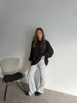 Pantalón de corte oxford con estampado de pequeñas manchas negras sobre fondo blanco. Presenta una silueta ajustada en la parte superior y acampanada hacia el ruedo.