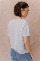 Sweater tejido celeste de manga corta con textura y delicadas líneas horizontales en relieve. Presenta cuello redondo y calce amplio con hombros caídos.