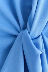 Top de punto color celeste, de manga larga amplia, con hombros caídos, escote redondo y detalle de nudo o giro drapeado en la cintura.