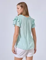 Blusa color verde agua con cuello redondo fruncido y lazo. Tiene mangas cortas con volados.