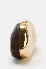 Bolso tipo clutch rígido con acabado metálico dorado y diseño de superficie irregular. Cuenta con cierre superior tipo clip y cadena metálica extraíble para usar como bandolera.