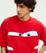 Pijama corto de hombre confeccionado en algodón, compuesto por una remera de manga corta con cuello redondo y estampa frontal de Rayo McQueen, y una bermuda roja a juego con cintura elástica.