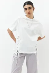 Remera blanca de algodón con cordones ajustables a los laterales, manga corta y cuello redondo.