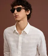 Camisa de manga larga color marrón óxido, con cuello inglés y abotonadura frontal. Presenta una textura grid sutil en el tejido.