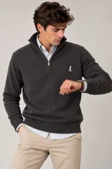 Buzo de punto fino color gris con cuello alto y medio cierre frontal, mangas largas y puños y ruedo elásticos de rib. Cuenta con un pequeño bordado en el pecho.