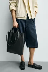 Bolso tipo shopper de diseño minimalista, confeccionado en piel con acabado abatanado. Cuenta con doble asa de mano y doble asa de hombro, compartimento principal amplio sin cierre y bolsillo interior plano.