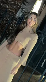 Polera corta de hilo color beige, con cuello alto y mangas largas acampanadas.