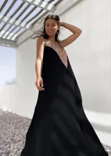 Vestido largo de fiesta color negro, con corte holgado y escote en V profundo decorado con lentejuelas doradas.