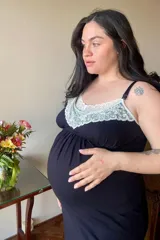 Camisón maternal de modal negro con detalle de puntilla blanca en el escote. Presenta breteles elásticos regulables con clip para lactancia y elástico bajo el busto para mayor sujeción.