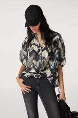 Camisa de manga corta con estampado abstracto en tonos blanco, negro y gris.