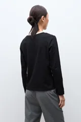 Remera de manga larga con diseño bicolor, presenta un panel central en color beige y laterales en color negro, con escote en V.