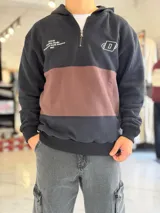 Hoodie de felpa con capucha y medio cierre frontal, diseño en bloques de color celeste y blanco, con bordados decorativos en el pecho.