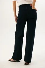 Pantalón de jean azul oscuro, de corte acampanado, con bolsillos delanteros y traseros, y costuras verticales en el frente.