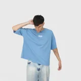 Remera de corte oversize color celeste, con cuello redondo y estampa gráfica pequeña centrada en el pecho.