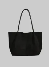 Bolso tipo tote de diseño minimalista en color negro, con textura suave y doble asa larga para llevar al hombro.