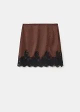 Minifalda marrón satinada con estampado de lunares negros y detalle de puntilla de encaje negro en el ruedo.