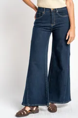 Jean de corte wide leg y tiro medio, confeccionado en denim de algodón. Presenta costuras verticales decorativas a lo largo de las piernas y cierre frontal con botón y cremallera.