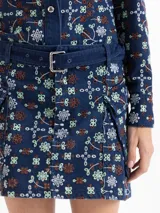 Minifalda de denim con diseño de guipiure floral, bolsillos cargo laterales y cinturón incorporado con hebilla metálica.