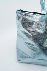 Bolso tipo tote bag color dorado con efecto arrugado y dos asas superiores.
