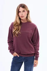 Buzo de cuello redondo en color bordó con efecto lavado, manga larga y detalle de tachas metálicas en la parte superior del pecho.